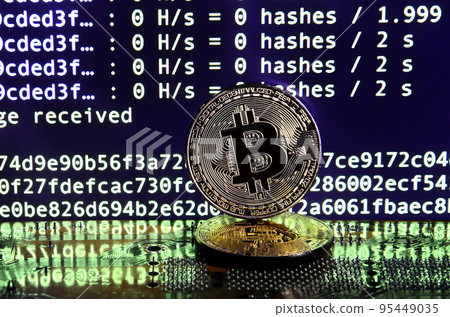 Two bitcoins lies on a videocard surface with background of screen display of cryptocurrency mining by using the GPUs 95449035
