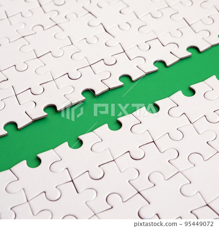 The green path is laid on the platform of a white folded jigsaw puzzle. Texture image with copy space for text The green path is laid on the platform of a white folded jigsaw puzzle. Texture image with copy space for text 95449072