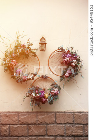 Decoration urban art object from bicycle wheels and flowers on wall Decoration urban art object from bicycle wheels and flowers on wall 95449153