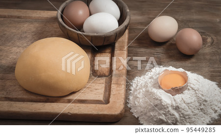 Egg noodle dough bun, with ingredients on the table. 95449285