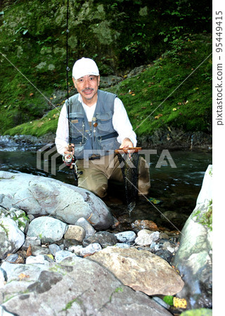 An angler who is happy holding up a caught char together with the landing net 95449415