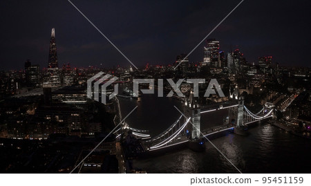 Aerial view to the illuminated Tower Bridge and skyline of London, UK, just after sunset at night time. Aerial view to the illuminated Tower Bridge and skyline of London, UK, just after sunset at night time. 95451159