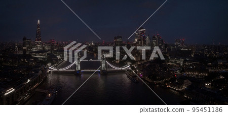 Aerial view to the illuminated Tower Bridge and skyline of London, UK, just after sunset at night time. Aerial view to the illuminated Tower Bridge and skyline of London, UK, just after sunset at night time. 95451186