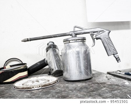 paint spray gun on wood table in car repair service center 95451501