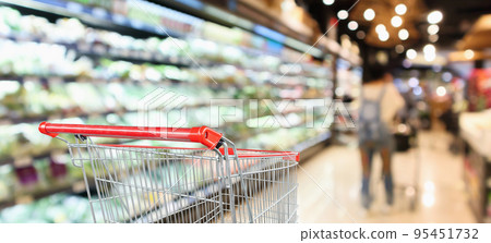 supermarket grocery store with fruit and vegetable shelves interior defocused background with empty red shopping cart 95451732