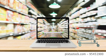 supermarket aisle blurred background with laptop computer and cart on wood table online shopping concept 95451900