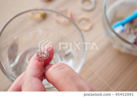 Jeweller hand cleaning and polishing vintage jewelry diamond ring closeup Jeweller hand cleaning and polishing vintage jewelry diamond ring closeup 95452091