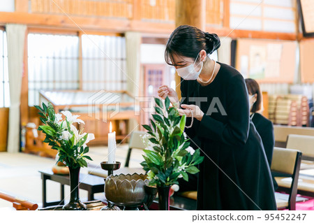 一位身穿喪服的女子在葬禮上燒香 95452247