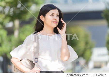 一個背著背包,用智能手機打電話的女商人 一個背著背包,用智能手機打電話的女商人 95452814