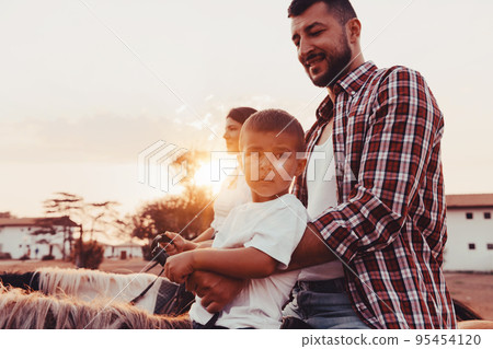 The family spends time with their children while riding horses together on a sandy beach. Selective focus  95454120