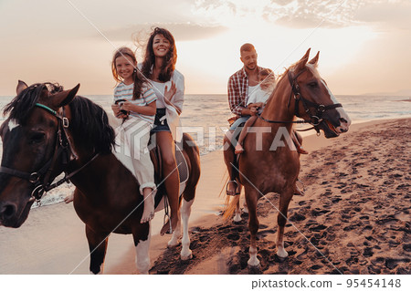 The family spends time with their children while riding horses together on a sandy beach. Selective focus The family spends time with their children while riding horses together on a sandy beach. Selective focus 95454148