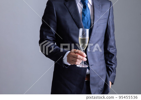 一個穿著西裝的男人端著一杯香檳 95455536