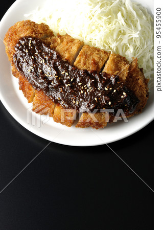 Overhead shot of shredded pork cutlet and cabbage with miso-based sauce on a black background 95455900