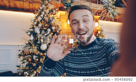 POV of attractive guy talking online holding camera making video call at New Year night, young man is congratulating family. People and communication concept. 95456092