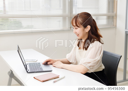 A woman who operates a personal computer in an office or rental space. An image of working comfortably online. A woman who operates a personal computer in an office or rental space. An image of working comfortably online. 95456300