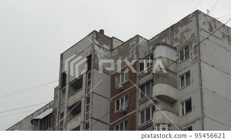 Concrete panel building close-up. The old building of the former USSR. Third world country. A tattered building against a backdrop of gray clouds. 95456621