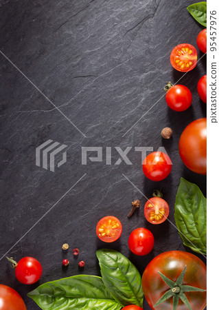 Fresh tomato and basil leaf at black slate background table. Salad ingredients on tabletop 95457976