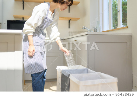 A woman sorting and throwing away garbage in the kitchen Garbage recycling image 95458459