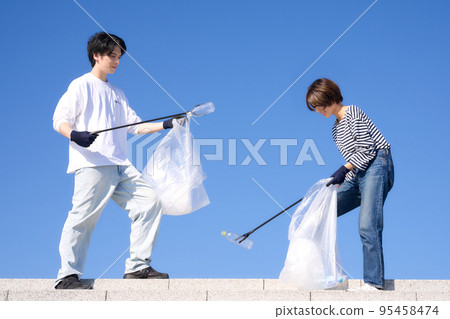 Young men and women picking up trash outdoors in sunny weather Volunteer cleaning image Young men and women picking up trash outdoors in sunny weather Volunteer cleaning image 95458474