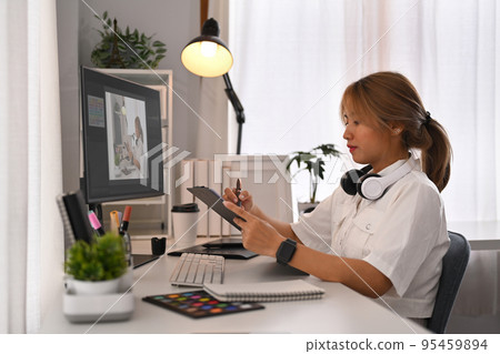 Creative woman using digital tablet, working on design project at graphic studio 95459894