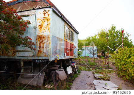 Post-apocalyptic housing. Old trailer in the forest. An antique wagon in an orchard among trees and bushes. Mechanisms and devices for scaring away from animals and birds in the garden. Wildlife Post-apocalyptic housing. Old trailer in the forest. An antique wagon in an orchard among trees and bushes. Mechanisms and devices for scaring away from animals and birds in the garden. Wildlife 95462636
