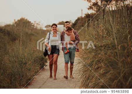 The family walks an idyllic path surrounded by tall grass. Selective focus The family walks an idyllic path surrounded by tall grass. Selective focus 95463898