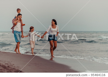 Family gatherings and socializing on the beach at sunset. The family walks along the sandy beach. Selective focus Family gatherings and socializing on the beach at sunset. The family walks along the sandy beach. Selective focus 95464116