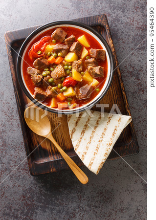 Fragrant lamb stew with carrots, potatoes, green peas and tomatoes close-up in a bowl. vertical top view Fragrant lamb stew with carrots, potatoes, green peas and tomatoes close-up in a bowl. vertical top view 95464390