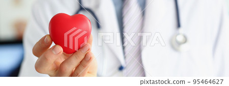 Man doctor hold red plastic heart and posing with stethoscope on neck Man doctor hold red plastic heart and posing with stethoscope on neck 95464627