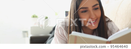 Young attractive woman reading book laying on couch at home, interesting story Young attractive woman reading book laying on couch at home, interesting story 95464640