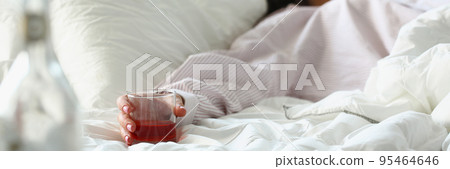 Woman in bed after fun night, hold glass with alcoholic drink, drunk female sleep 95464646