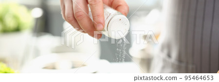 Professional cook hold saltcellar and add salt to soup against kitchen background Professional cook hold saltcellar and add salt to soup against kitchen background 95464653