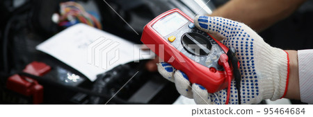 Mechanics hand hold multimeter equipment to measure voltage of automobile battery 95464684