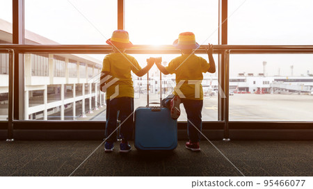 Child with suitcase at airport terminal waiting for departure looking out the window. Child with suitcase at airport terminal waiting for departure looking out the window. 95466077