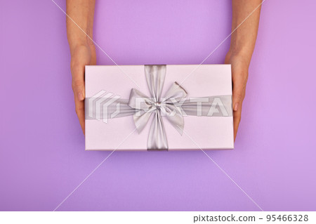 Hands holding blue gift box pink background 95466328