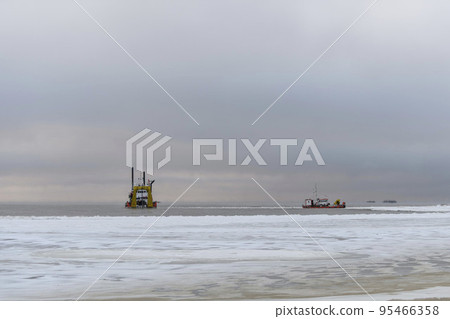 Vessel engaged in dredging at sunset time. Hopper dredger working at sea. Ship excavating material from a water environment. Vessel engaged in dredging at sunset time. Hopper dredger working at sea. Ship excavating material from a water environment. 95466358