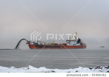 Vessel engaged in dredging at sunset time. Hopper dredger working at sea. Ship excavating material from a water environment. 95466362