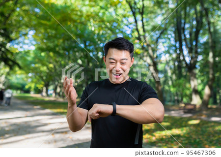 Sport Caucasian man looking smart watch at modern track runner using use smartwatch fitness bracelet Portrait fit male athlete checking result jogging in sportswear in street urban city park outdoor 95467306