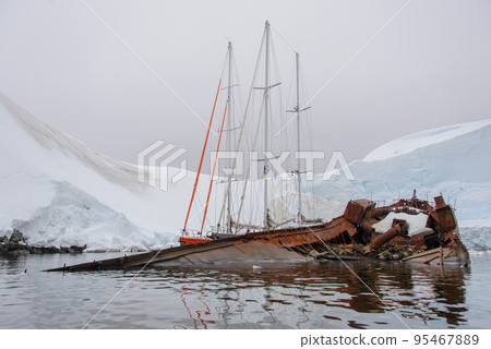 Two sailing yachts in the antarctic sea moored to rusty wreck Two sailing yachts in the antarctic sea moored to rusty wreck 95467889
