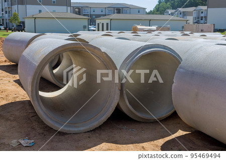 On construction site large cement sewage concrete pipes were used to construct drainage systems for industrial buildings in area. 95469494