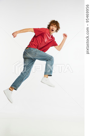 Full length portrait of excited young man running, dancing, having fun isolated over white background. Sport, dance, fitness, happiness 95469956