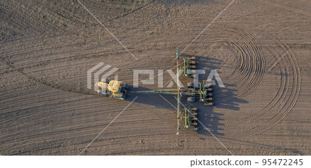 Spring field work, a tractor with a mounted seeder sow seeds in the ground 95472245