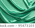 Light Green Satin Background. Beautiful pale emerald green luxury satin fabric texture with light wavy folds. 95473103