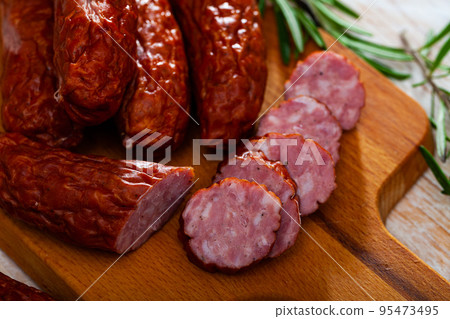 Sliced half-smoked sausages susena on wooden table. Traditional Chezh meat products Sliced half-smoked sausages susena on wooden table. Traditional Chezh meat products 95473495