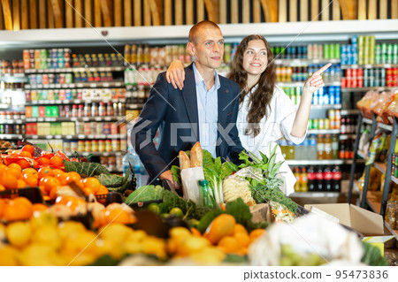 Portrait of a happy young couple with products in a cart in the supermarket 95473836