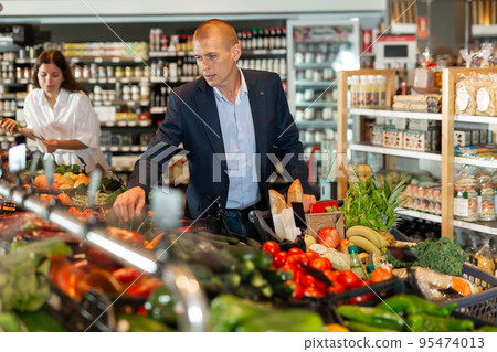 Portrait of a focused young male with a grocery cart in the supermarket 95474013