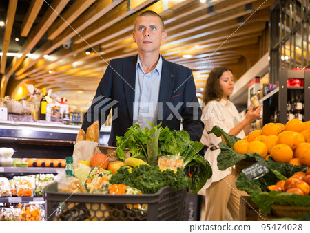 Portrait of a confident young couple in the supermarket Portrait of a confident young couple in the supermarket 95474028