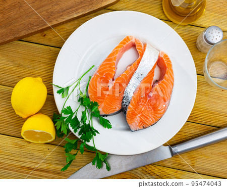 Raw salmon steaks, parsley, garlic and lemon on plate 95474043