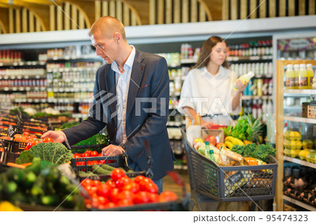 Man shopping at vegetables department of supermarket Man shopping at vegetables department of supermarket 95474323