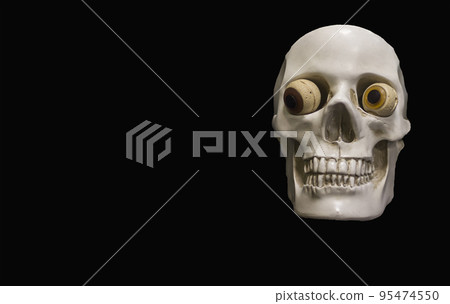 Clay skull on a black background. Cheerful eyes on the skull 95474550